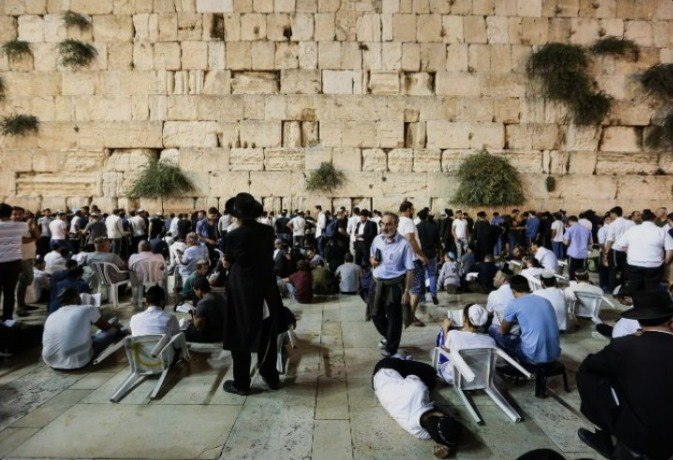 Jewish men sitting on low stools reading Kinot on Tisha B'Av 